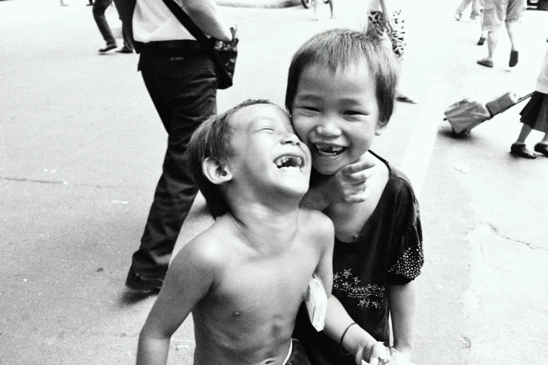 two s laughing while sitting on the sidewalk