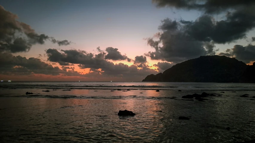 the ocean at sunset with clouds and water covering it