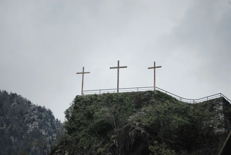 three crosses overlooking a hill with trees