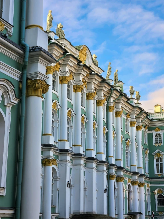 row of old white and gold painted buildings with clock tower in background