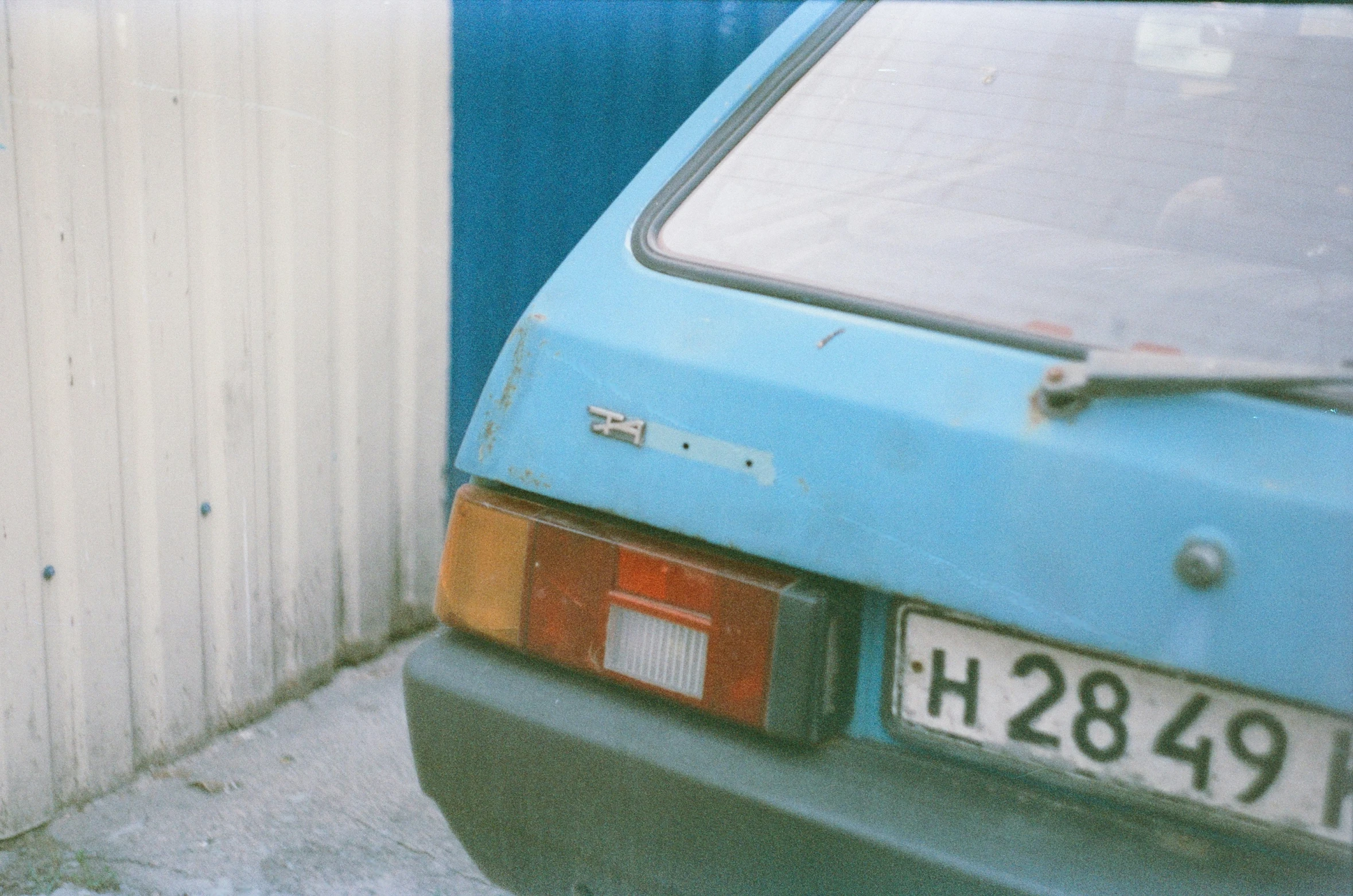 a car is parked by the side of a white wall