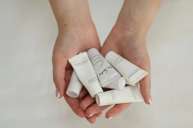 four small tubes of cream in someone's hands