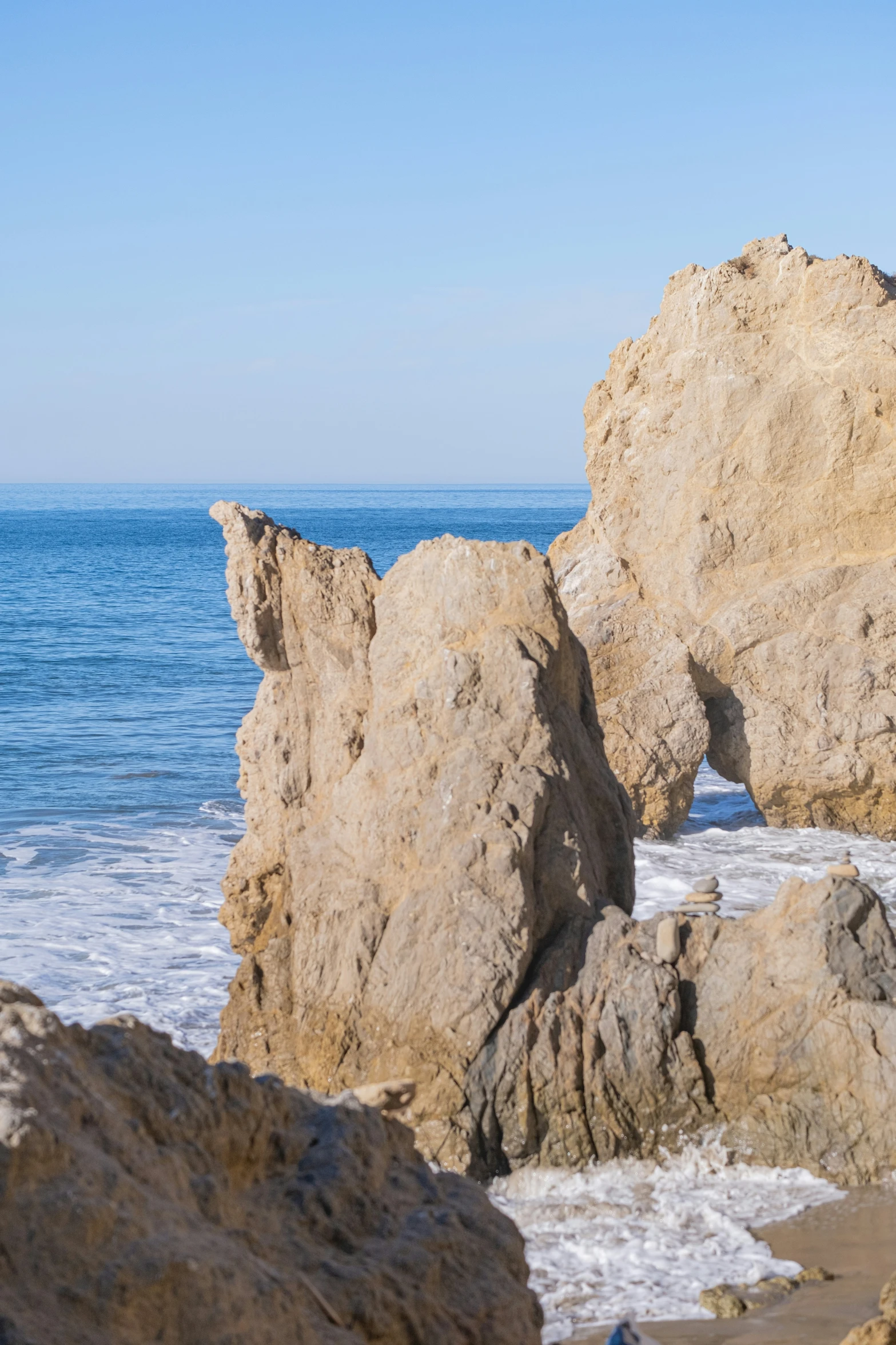 two large rocks are sitting on the beach near the water