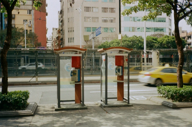 a double - pay phone booth stands on a street corner