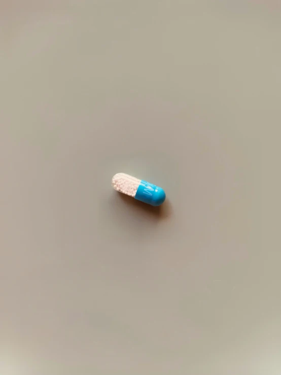 a blue and white pill sitting on top of a gray surface