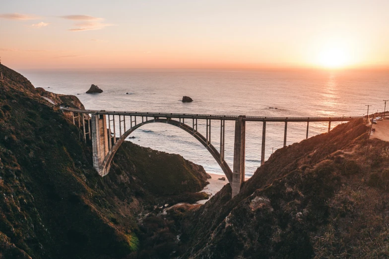 a road that has a bridge over it by the ocean