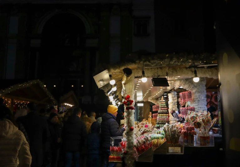 a crowd of people stand outside a building covered in lights