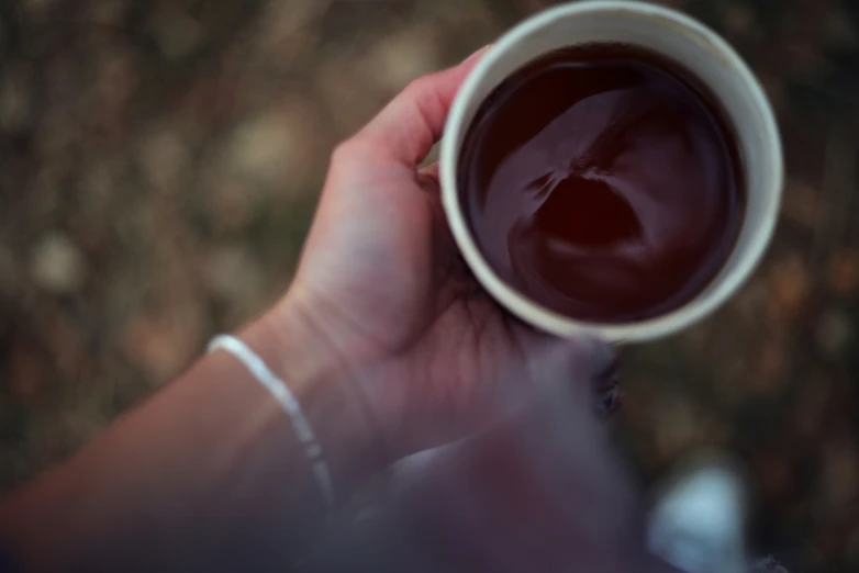 the person is holding the mug outside with chocolate on it