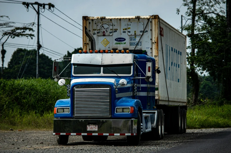 a semi is traveling on the road beside the woods