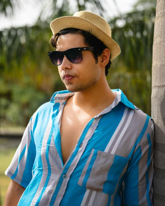 a man wearing a blue shirt, gray and white hat and sunglasses
