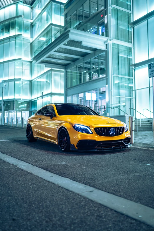 yellow mercedes s - class coupe with a metallic exterior parked outside an industrial building