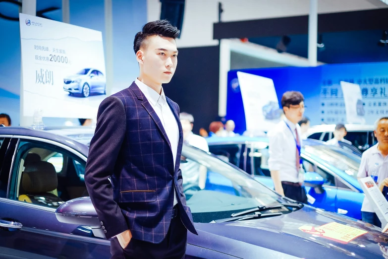 a man in a suit standing next to two cars