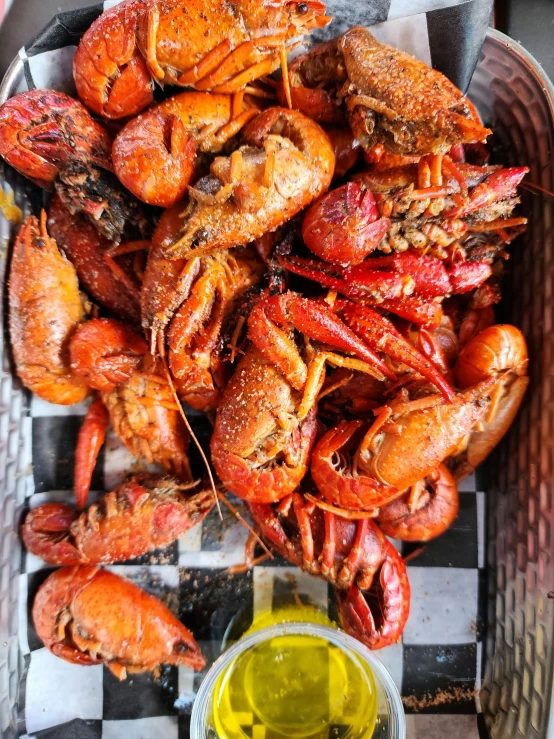 a tray holding several large cooked lobsters and a small glass of mustard