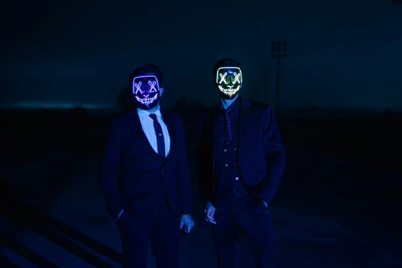 two men wearing neon masks pose for the camera