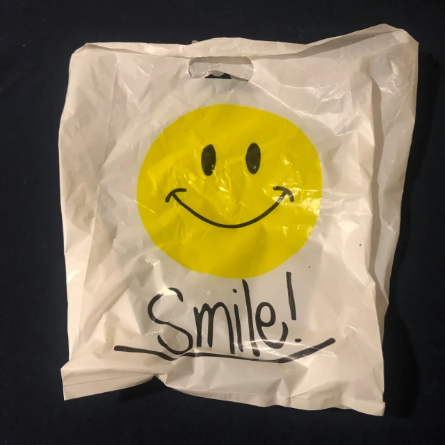 white bag with yellow smiling face on the front