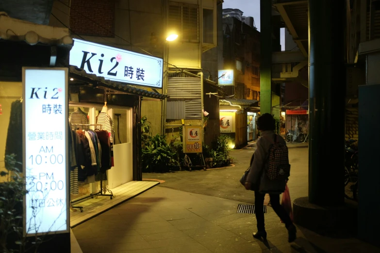 a person walking down a street at night with clothes