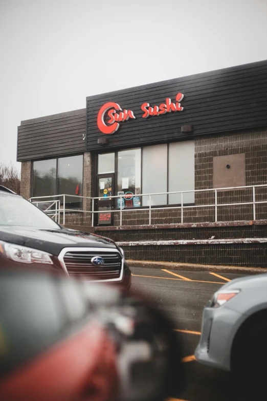 cars drive near a very large restaurant on a street