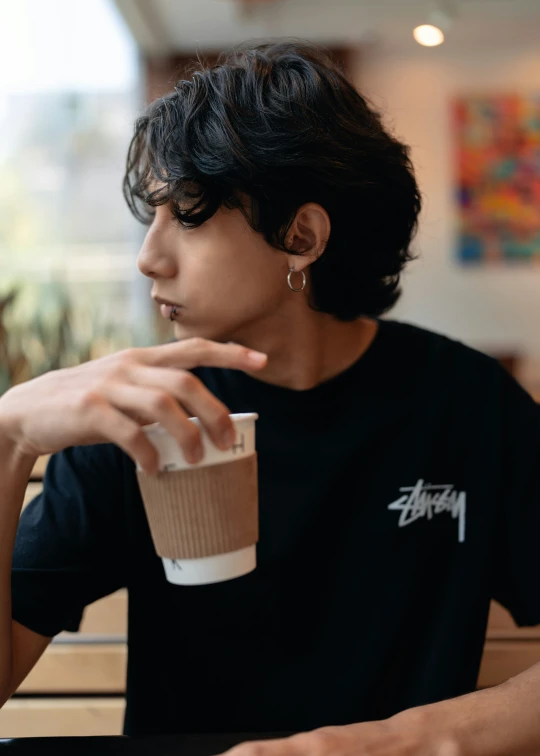 a person in black shirt sitting and drinking a coffee