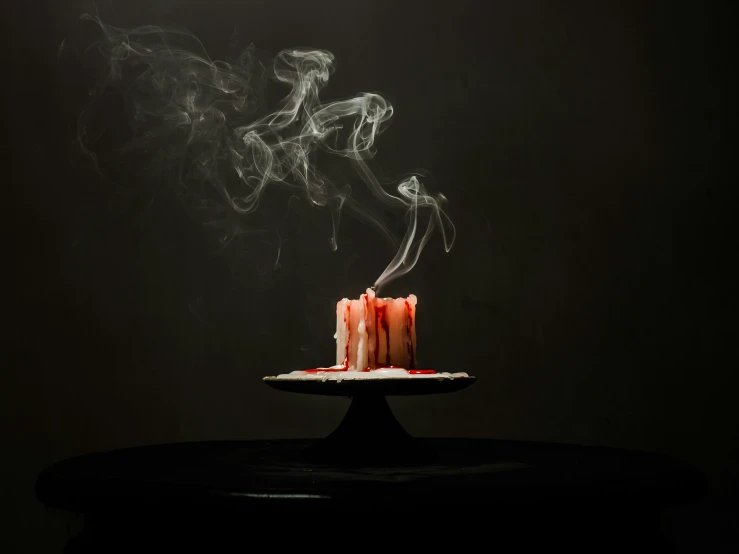 smoke rising from the top of a pink cake on a plate