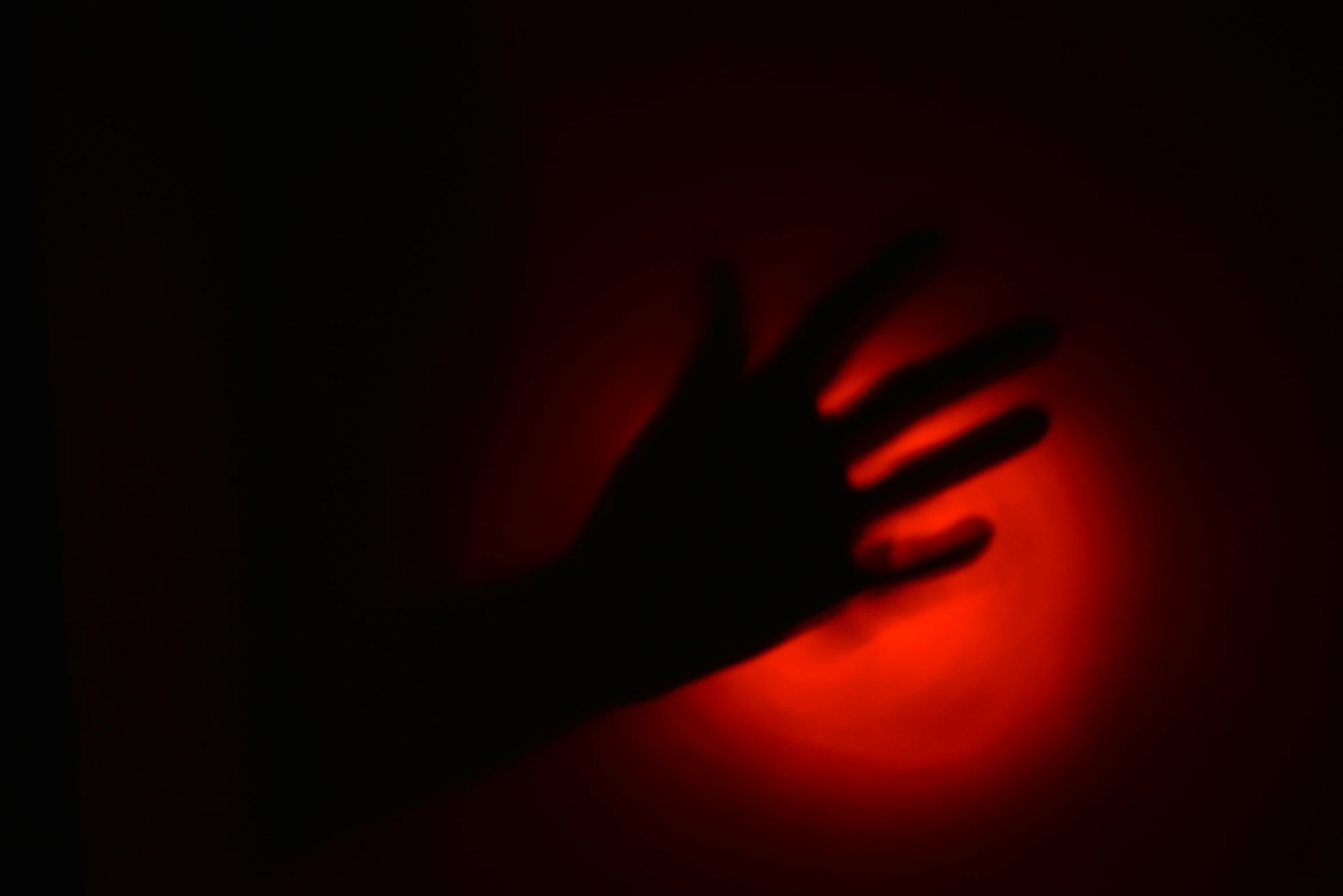 a hand coming out from underneath an object in a dark room