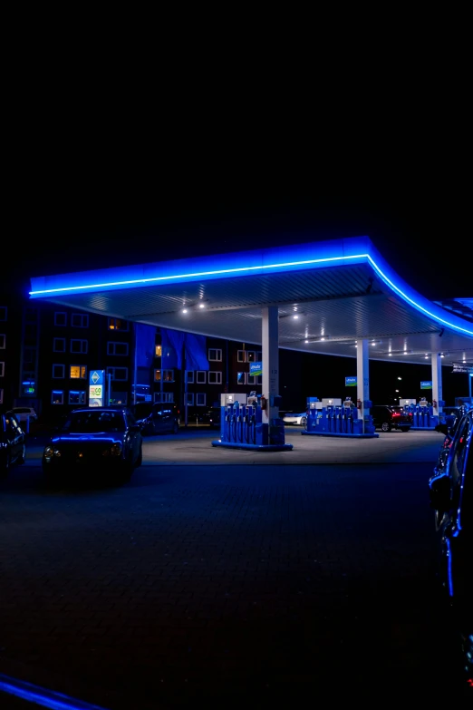 a gas station in the night with neon lights on it