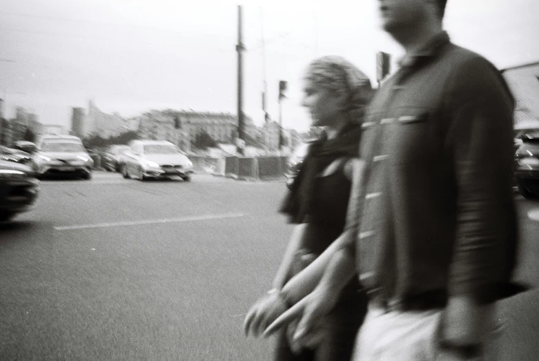 a black and white po of two people crossing the street