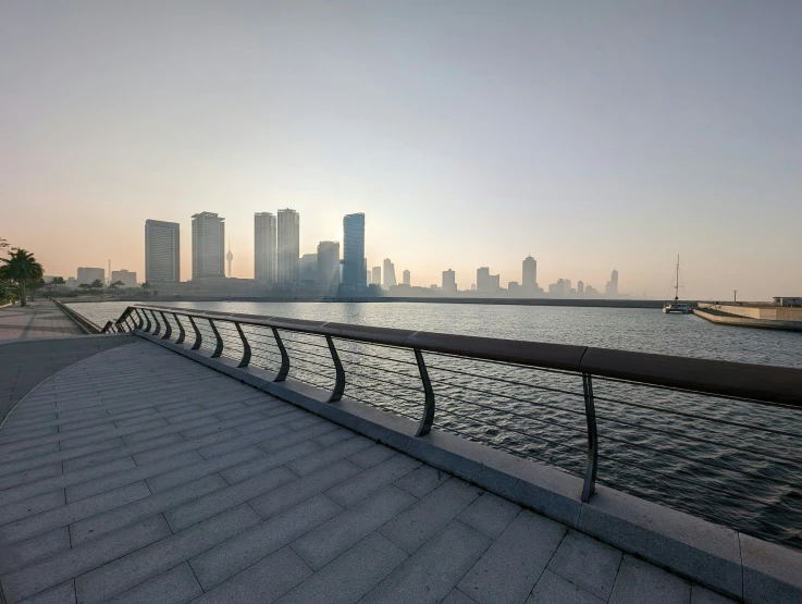 a walkway near a body of water in front of a city skyline