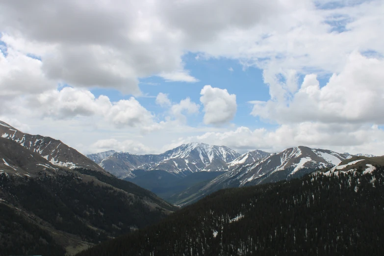 the snow capped mountains are covered in trees