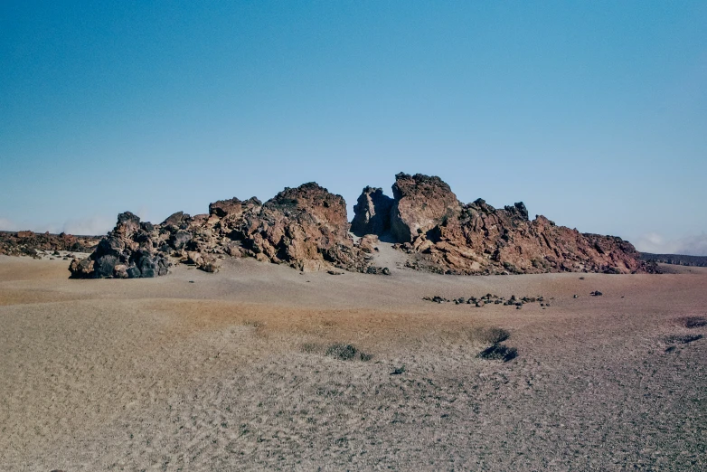 a rocky outcropping is seen in the middle of a desert