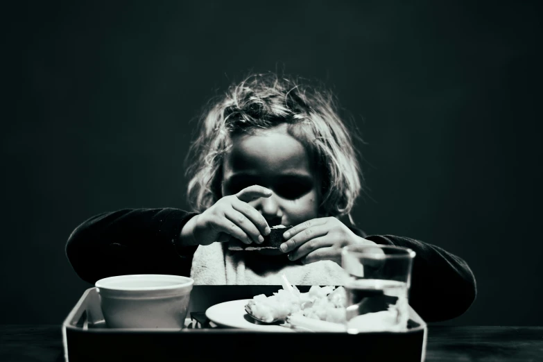 a woman sitting at a table eating with her hands