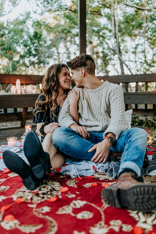 a couple cuddle while on the ground in a park