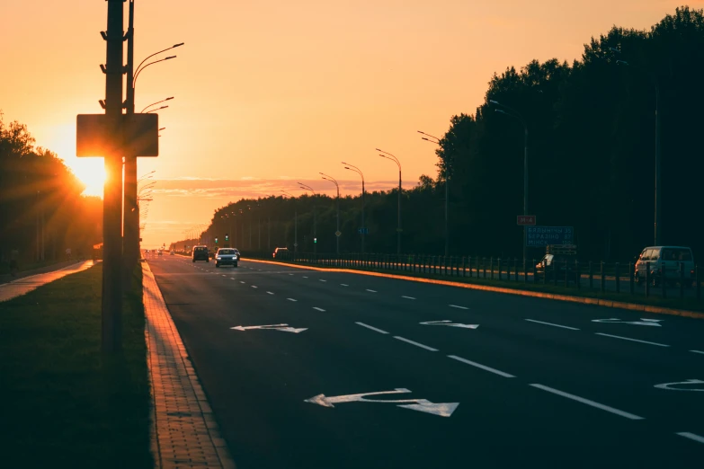 a sunset on an open street with two lanes