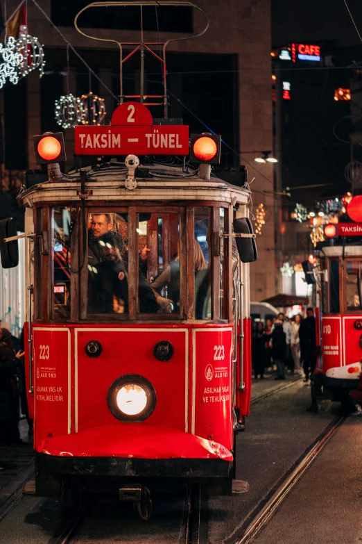 an older red trolly is moving down the streets