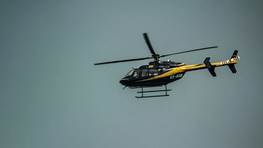 a black and yellow helicopter flying in the air