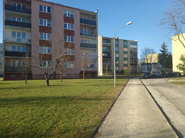 a paved pathway runs beside several multi - story buildings