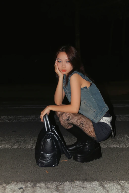 a woman is squatting on the ground with her luggage