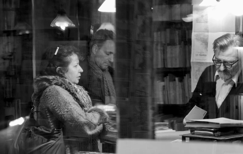 a man and woman standing in a room looking at books