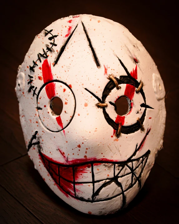 a half painted white mask with red, black and white designs on it