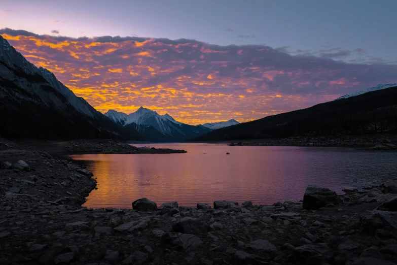 a mountain range is seen at sunset with a body of water