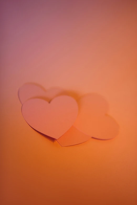 three paper hearts sitting next to each other on an orange background