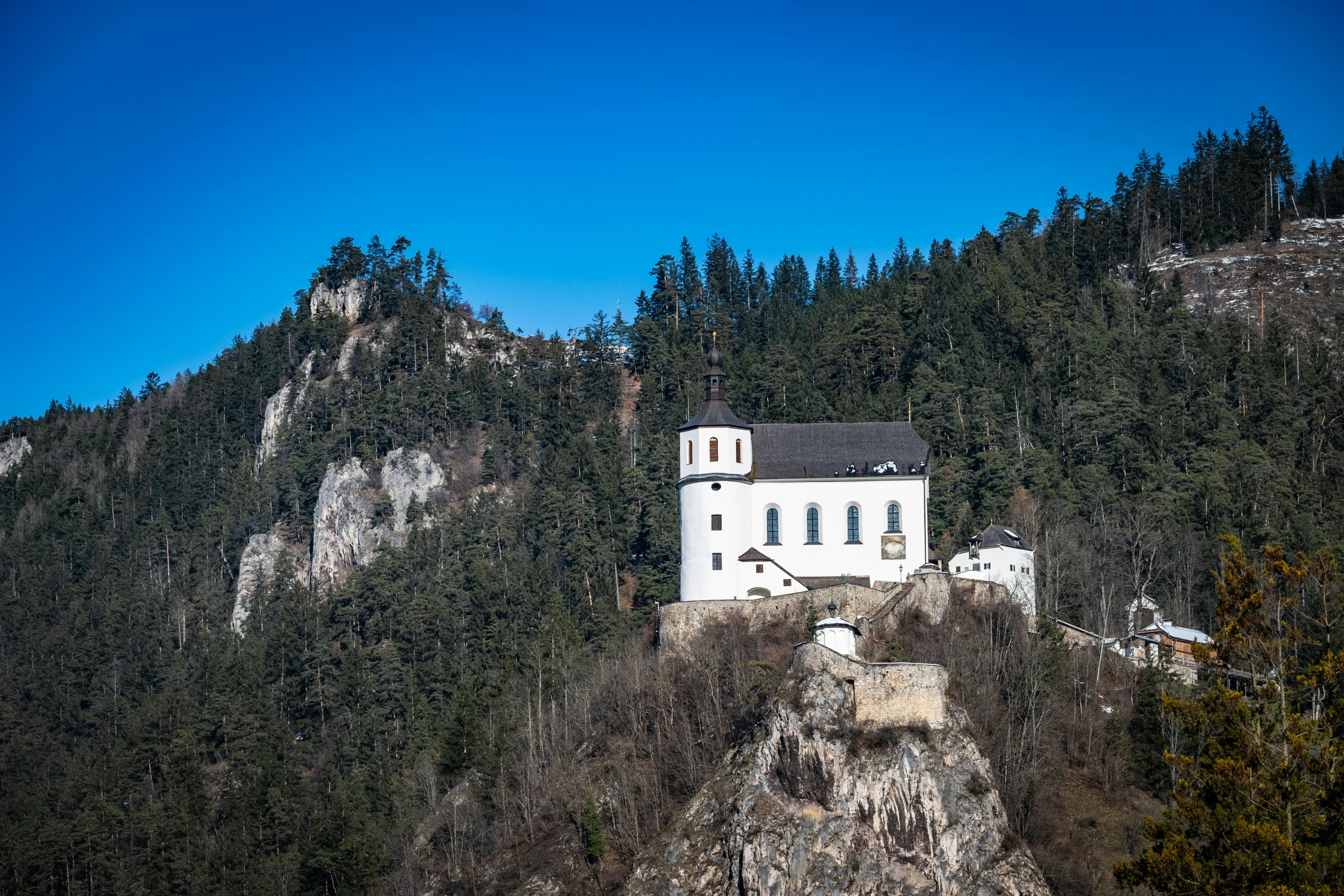 a white house in a mountain side forest