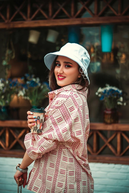 a woman standing on the sidewalk holding a small cup of coffee