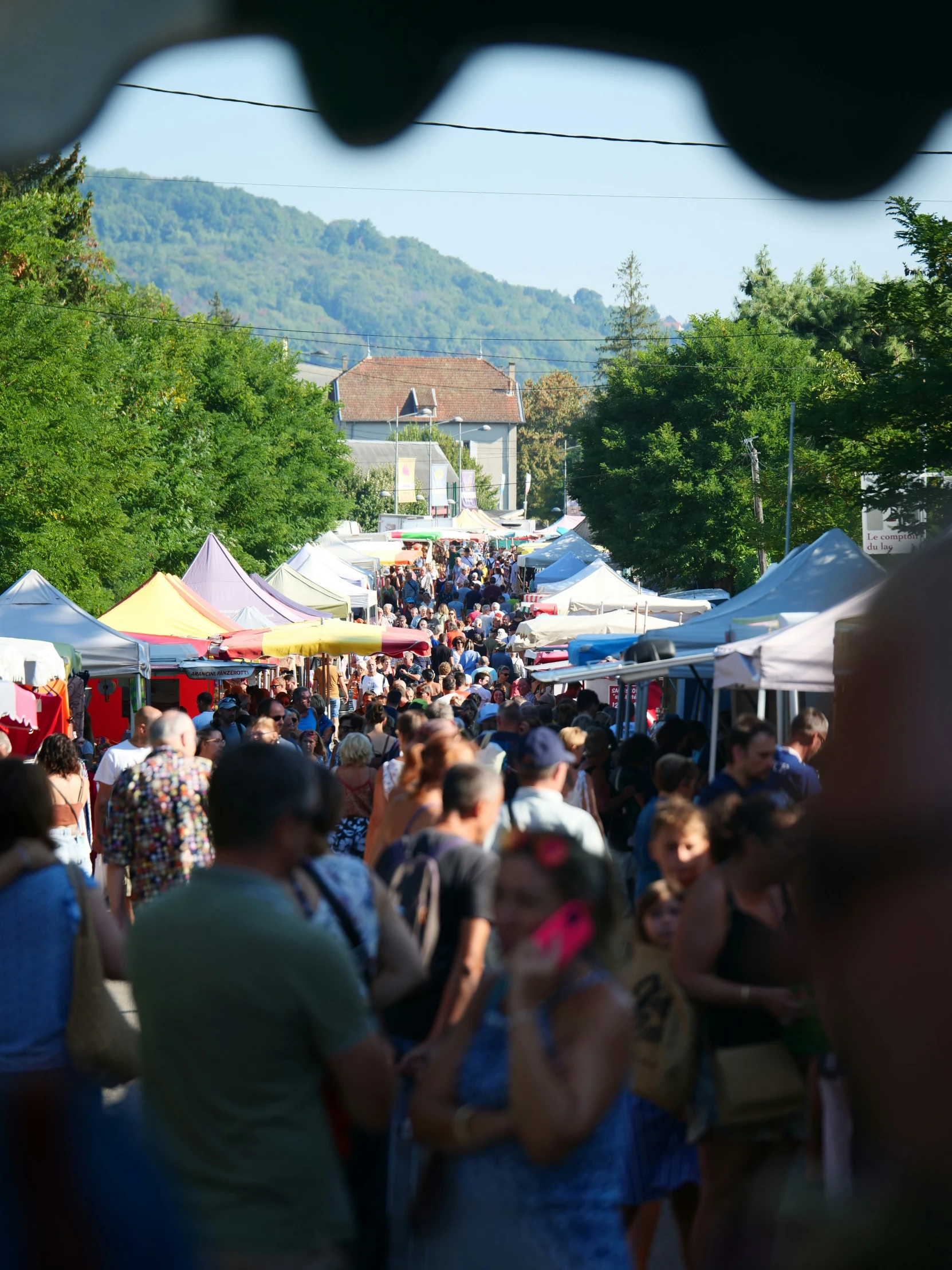 a crowded street filled with lots of people and tents