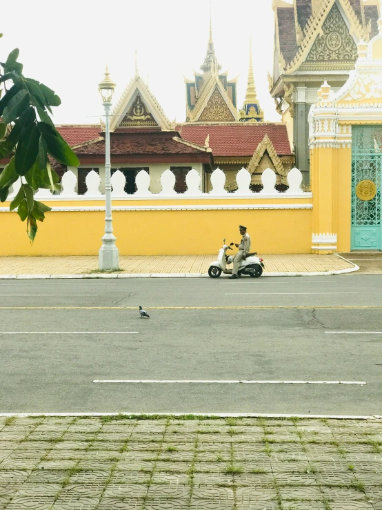 a couple on a moped ride by an ancient building