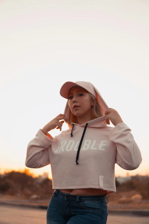 a woman standing wearing a pink hoodie