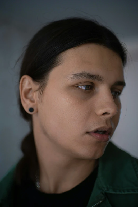 a woman in a green jacket is staring into the distance