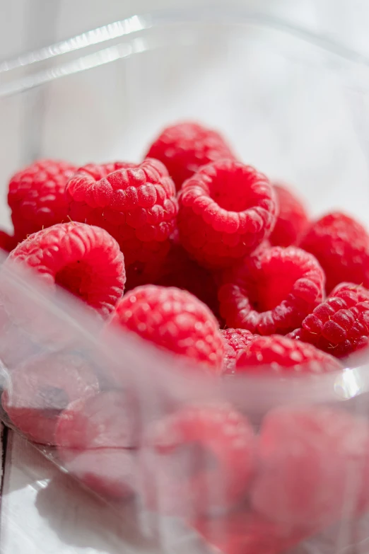 a clear plastic container filled with raspberries