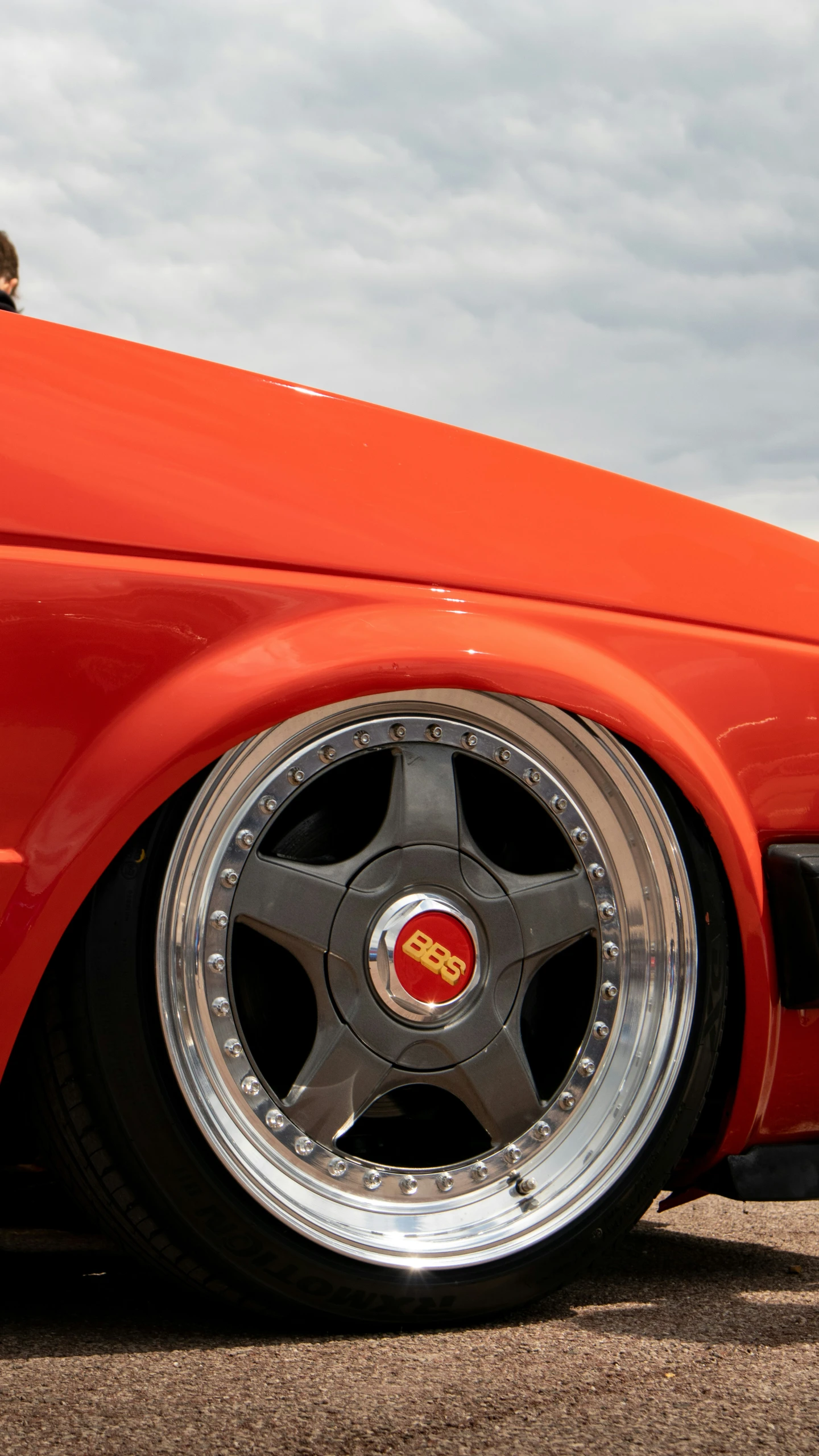 the front of an orange sports car with chrome wheels