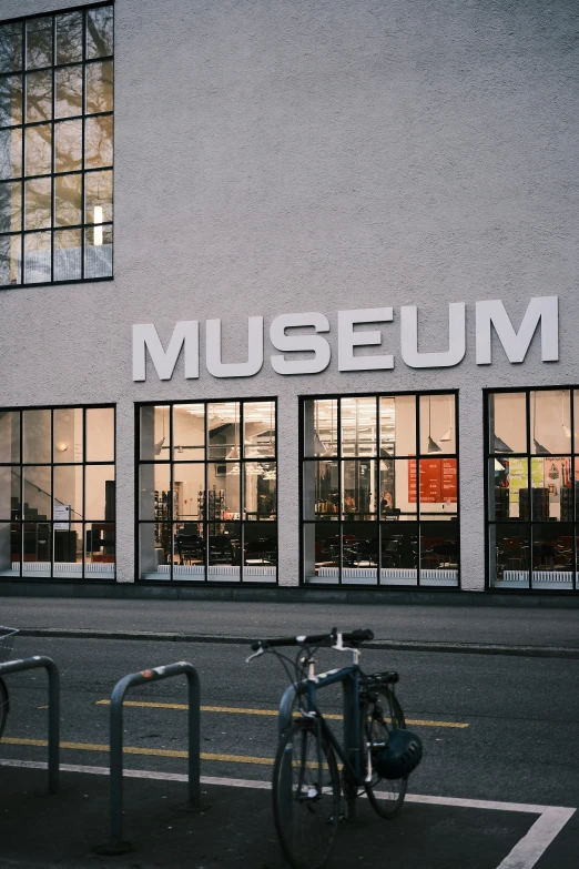 the reflection of people standing next to a bicycle parked outside of the museum