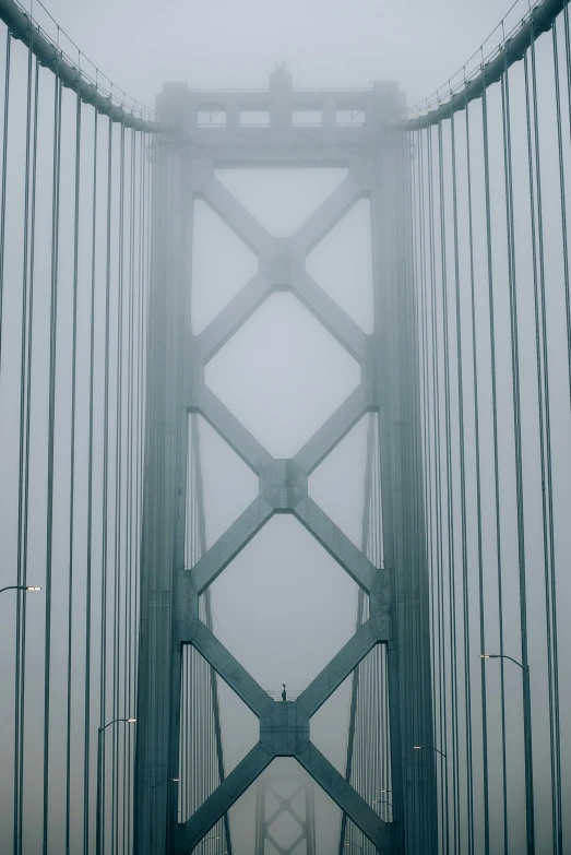 a bridge in the fog is shown from an empty street